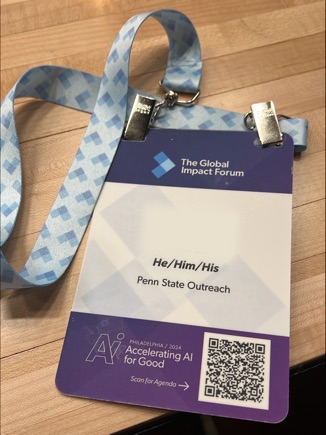 Closeup of a conference badge and printed lanyard featuring a blue and white arrow pattern.