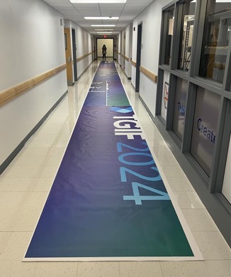 Large green and blue printed banners drying in a hallway.